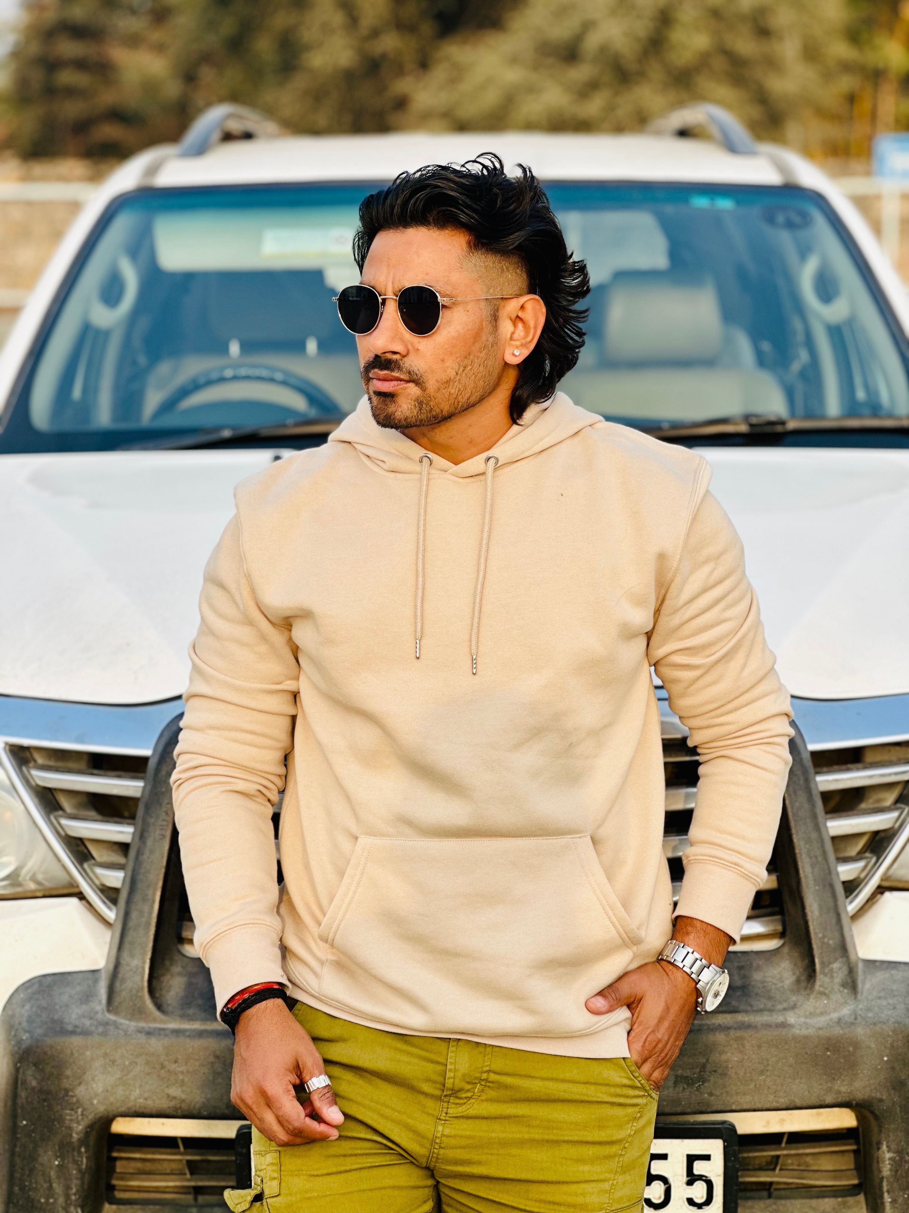 Confident man in sunglasses posing with a relaxed style in front of an SUV.