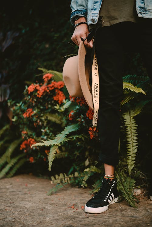 Person In Black Pants Holding A Hat