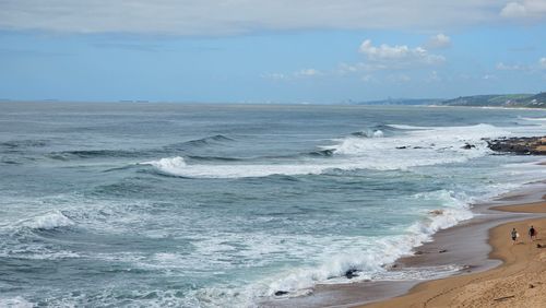 Free Expansive ocean view with waves crashing on a sandy shore under a clear blue sky. Stock Photo