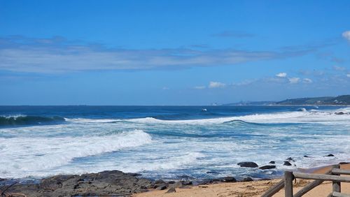 Free Breathtaking coastal landscape with waves crashing on the shore under a clear blue sky. Stock Photo