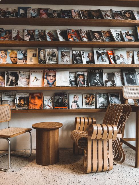 Stylish reading nook with wooden chairs and a collection of fashion magazines.