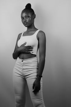 Stylish black and white portrait of a young woman in a tank top, capturing elegance and poise.