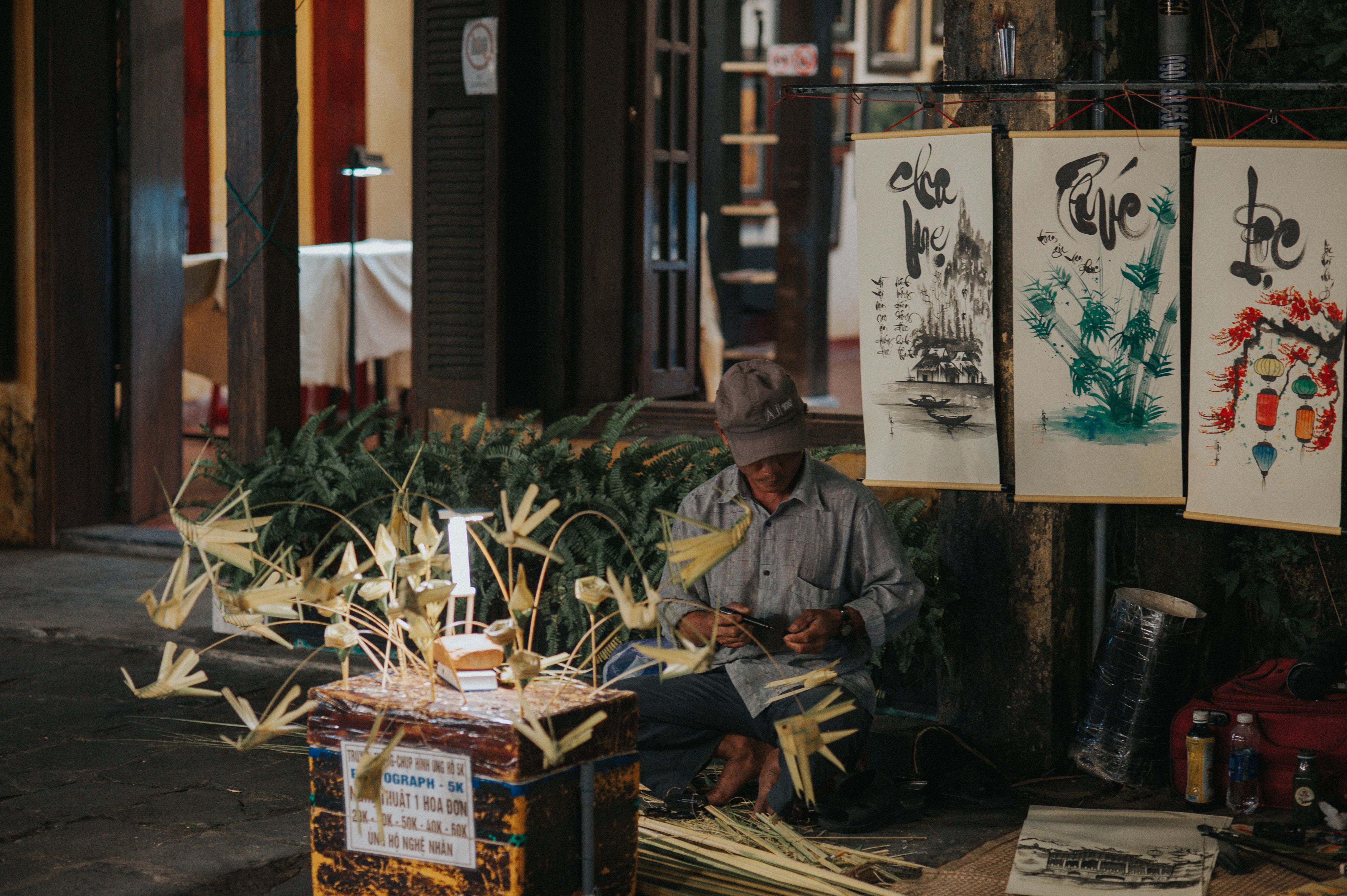 Street artist skillfully crafting traditional art pieces in an urban town setting. Captivating cultural display.