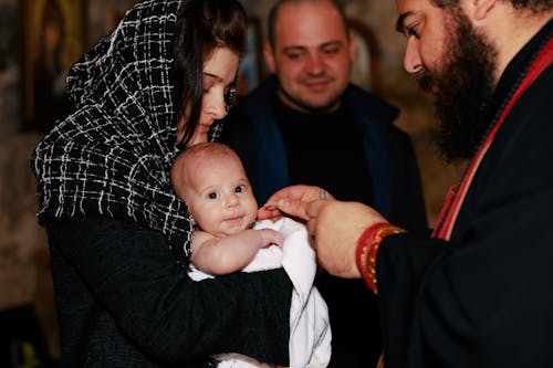 Mother Holding Smiling Baby at Baptism Ceremony