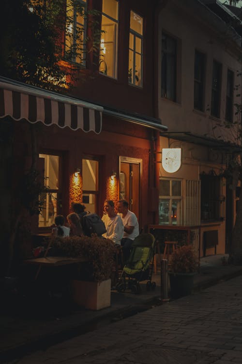 Free People sitting outside a restaurant at night Stock Photo