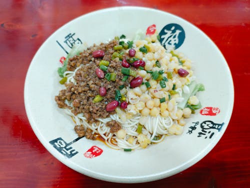 A white plate with noodles and meat on it