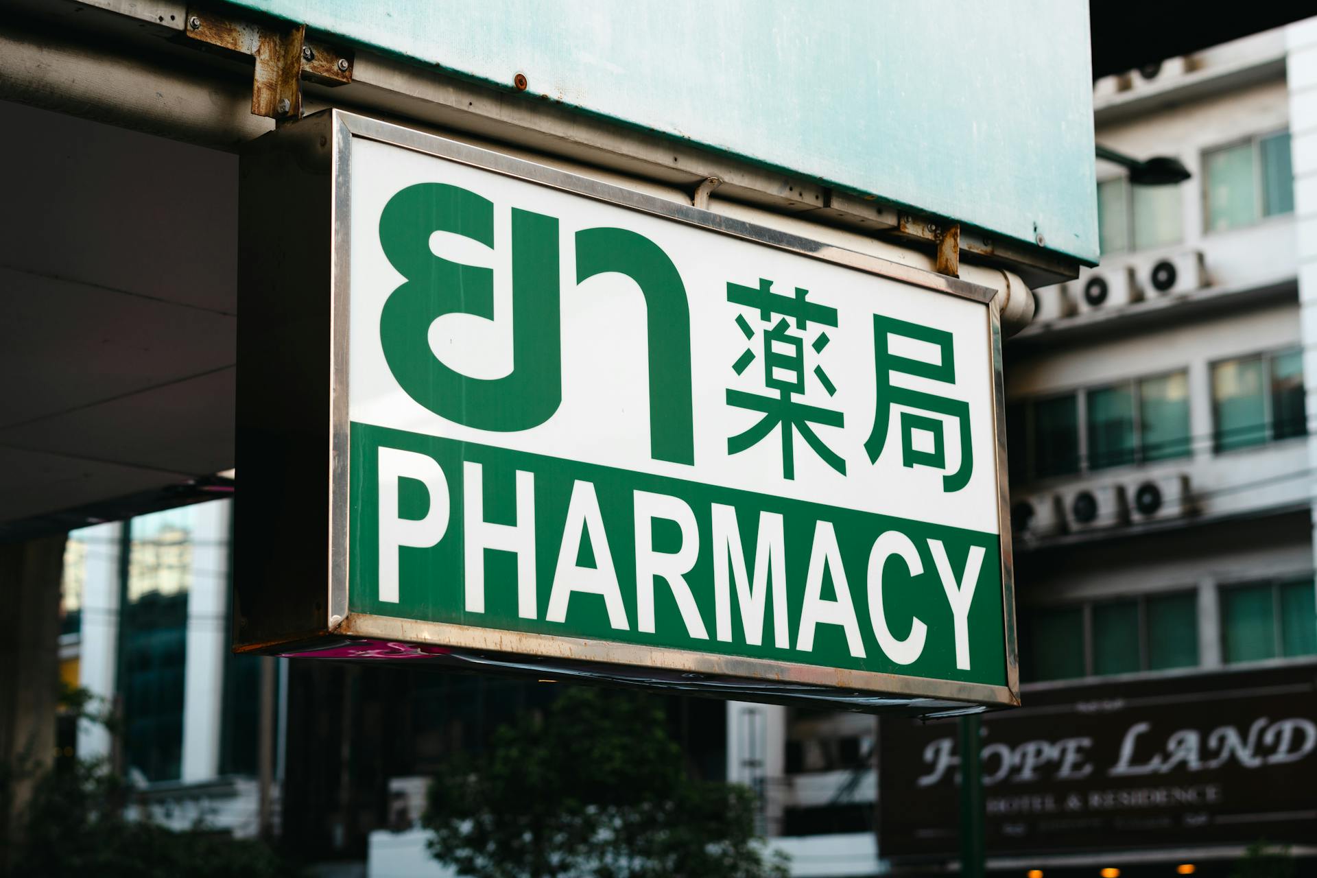 A pharmacy sign hanging from a building