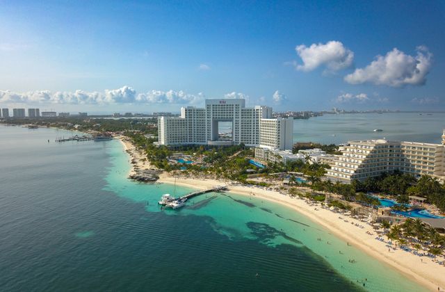A stunning aerial view of a hotel on the Cancún beachfront, showcasing the coastline and sea. — arriving in Cancún