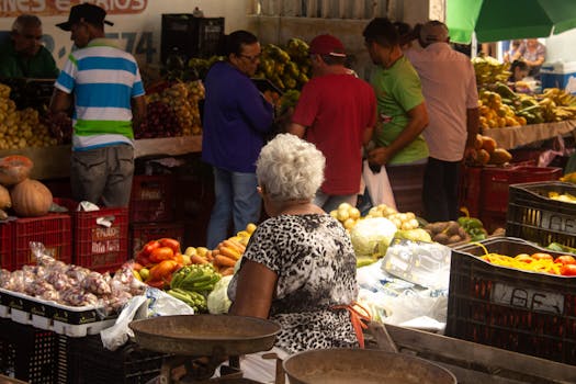 A vibrant market scene with people buying and selling fresh produce in an urban setting.