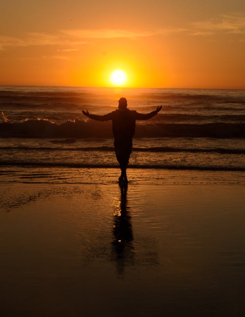 Silhouette of a Man Standing on a Beach at Sunset
