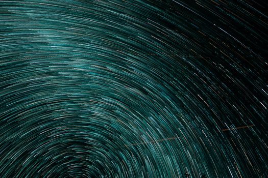 Dynamic turquoise star trails creating a swirling vortex in a captivating abstract pattern.