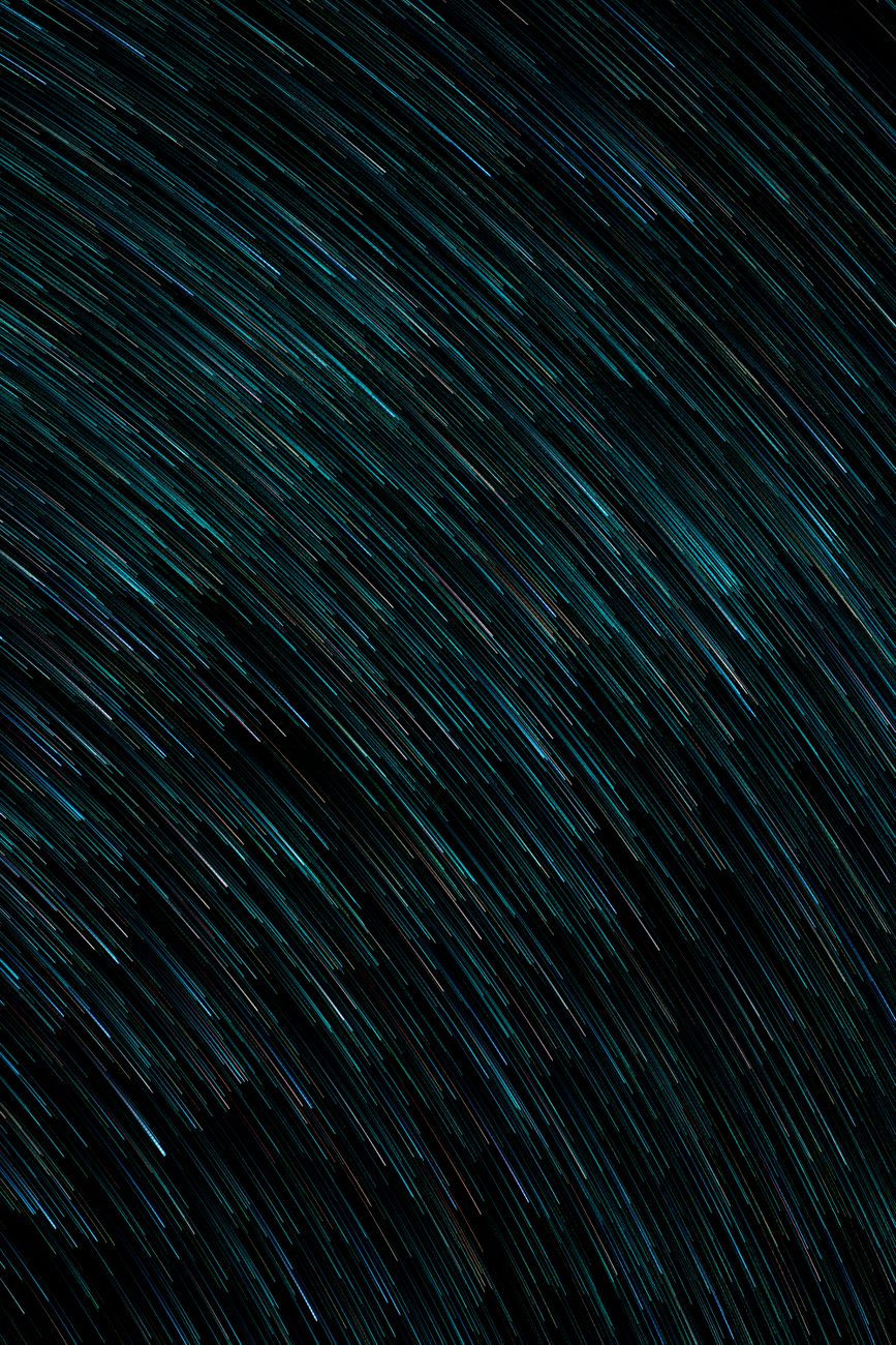 Dynamic abstract image with turquoise light trails on a dark background, ideal for modern design.