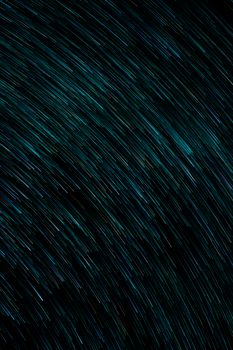 Dynamic abstract image with turquoise light trails on a dark background, ideal for modern design.