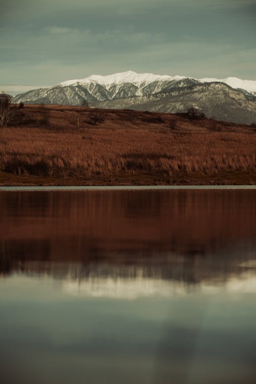 A lake with snow capped mountains in the background