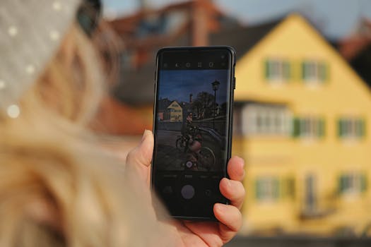 Close-up of person using smartphone to capture a scenic urban setting on a sunny day.