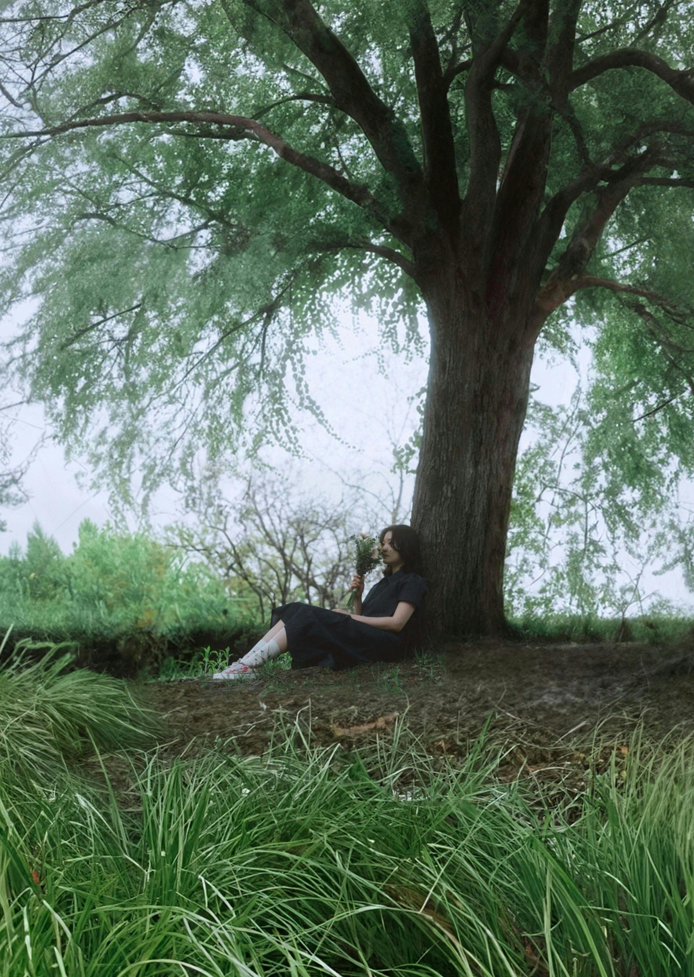 Serene image of a woman sitting under a large tree in a lush green field.