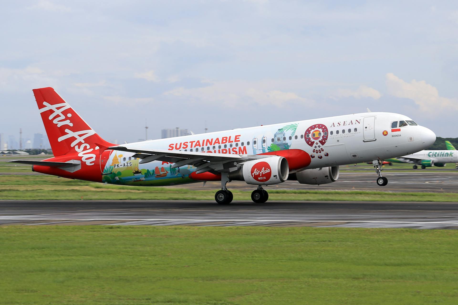 AirAsia commercial jet showcasing vibrant sustainable tourism theme on airport runway.