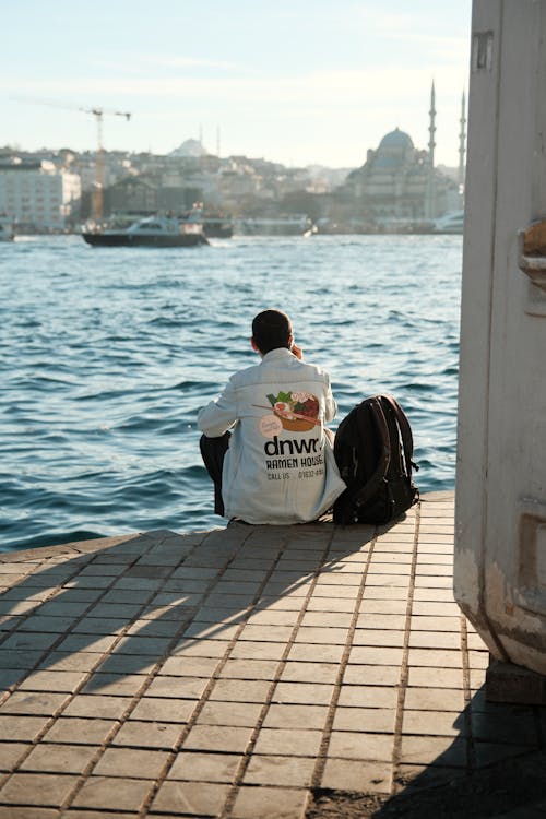 Back View of a Man Sitting on the Shore of the Bosphorus Strait in Istanbul 