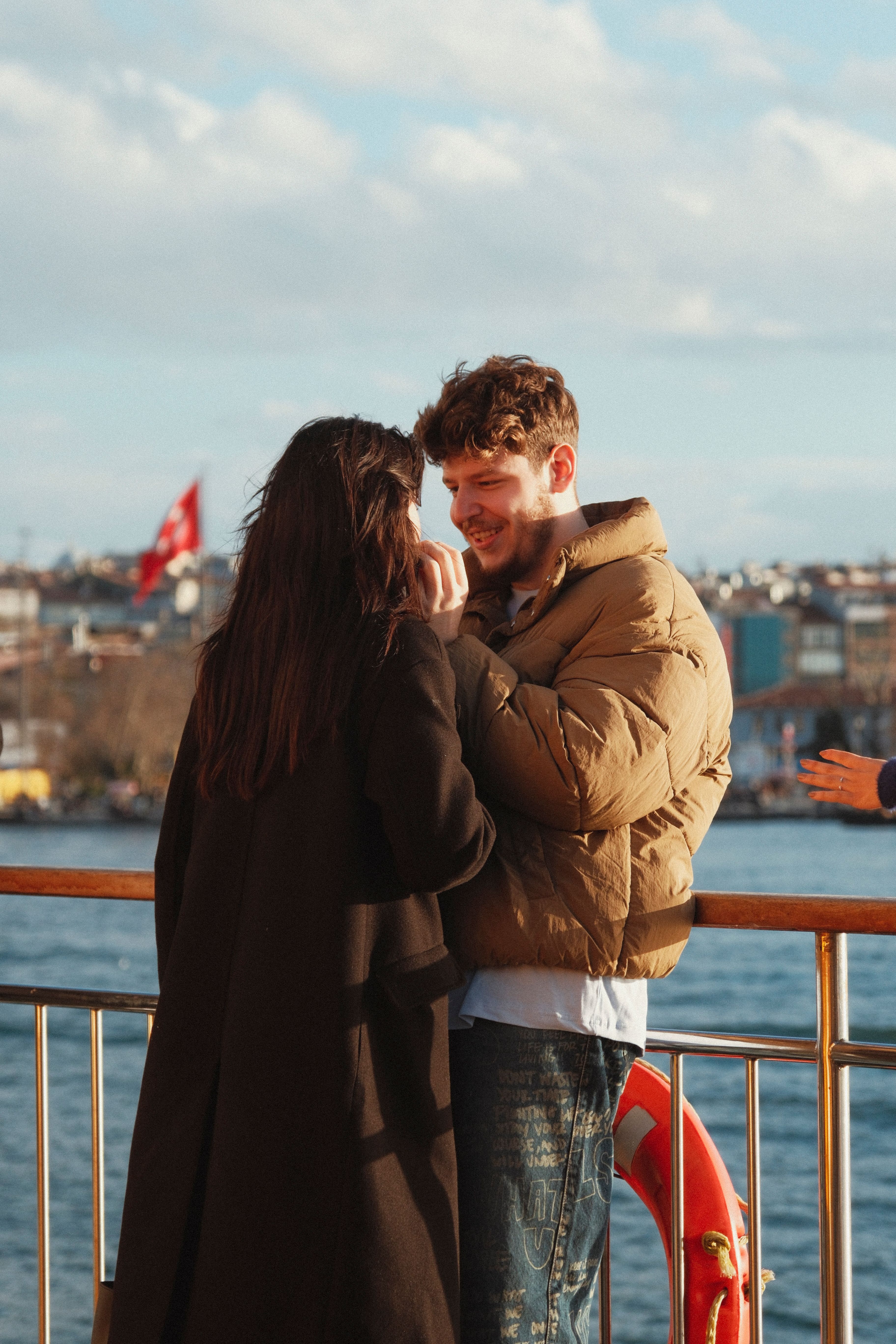 A young couple embraces on a ferry in Istanbul, capturing a moment of love and happiness.