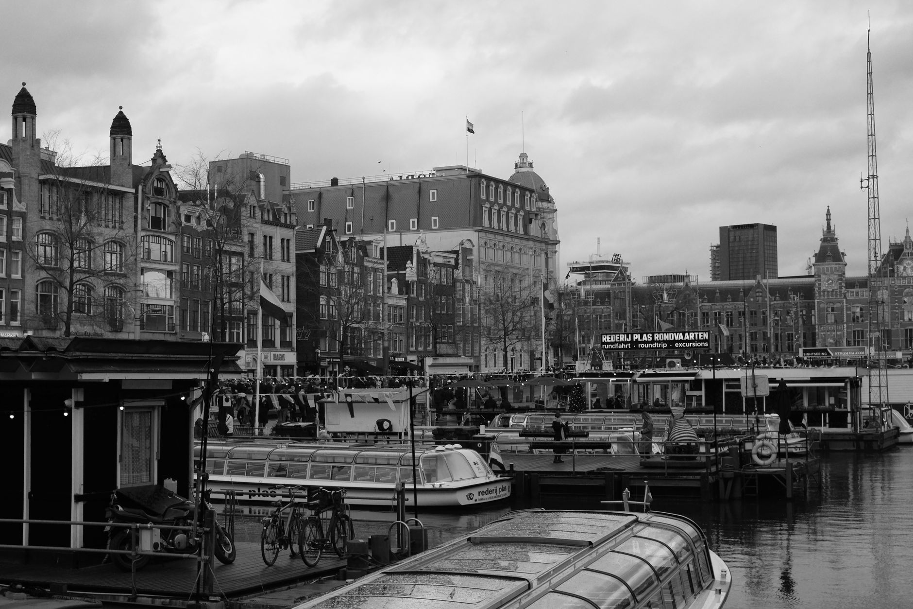 Black and white photo capturing Amsterdam's canals and historic buildings under a cloudy sky.