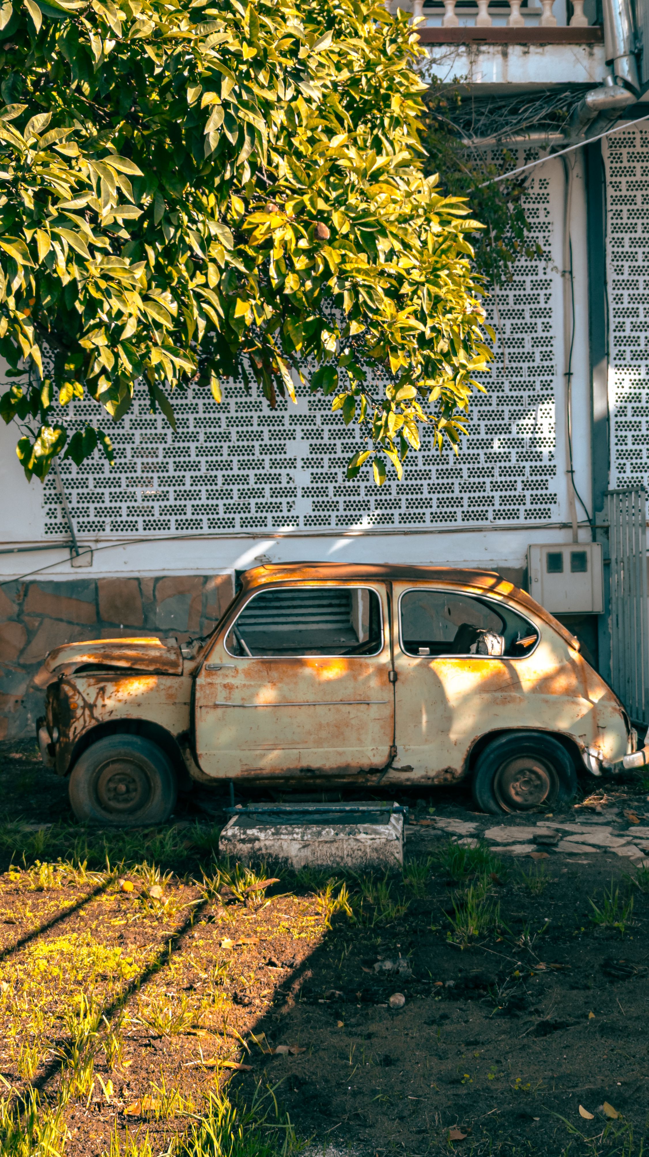 An Abandoned, Rusty Car Parked near a Building · Free Stock Photo