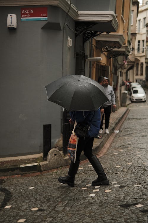 A person walking down a cobblestone street with an umbrella