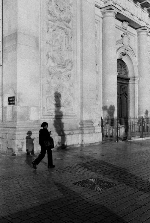Black and White Photo of a Woman Walking near a Church 