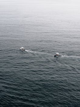 从空中俯瞰，两艘船在平静的海面上航行，划出细微的波浪