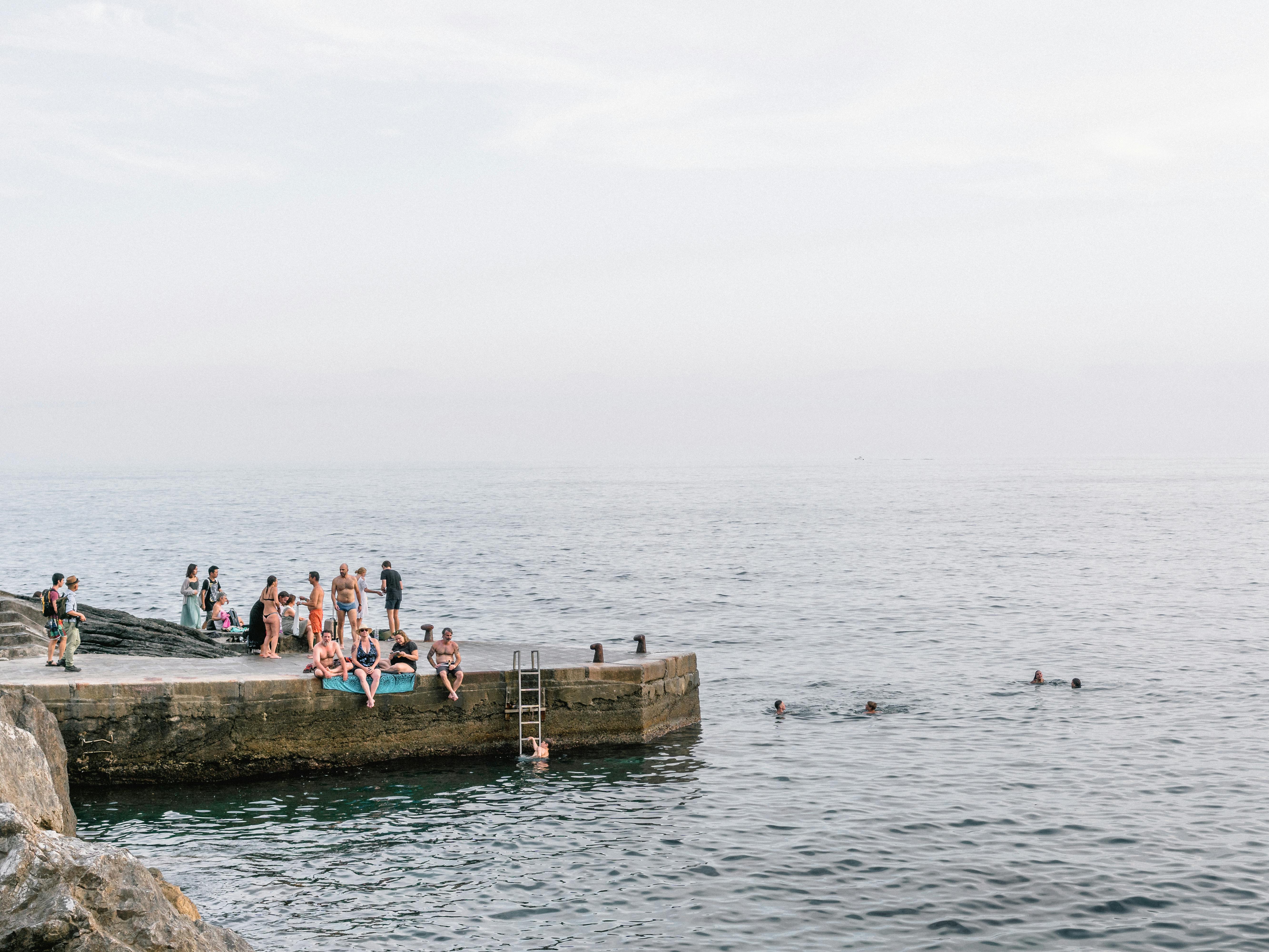 晴朗的日子里，一群人在海滨码头游泳放松，尽显夏日悠闲