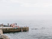 晴朗的日子里，一群人在海滨码头游泳放松，尽显夏日悠闲