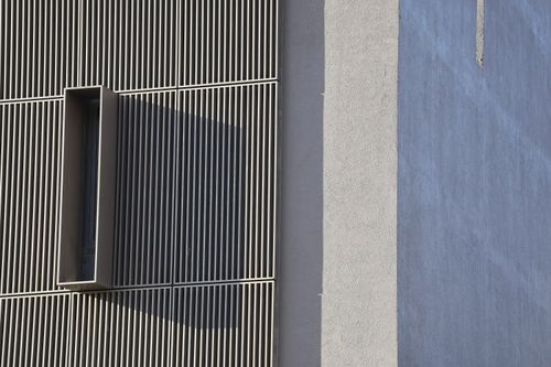 Free Close-up of a modern building facade featuring vertical lines and dramatic shadows. Stock Photo