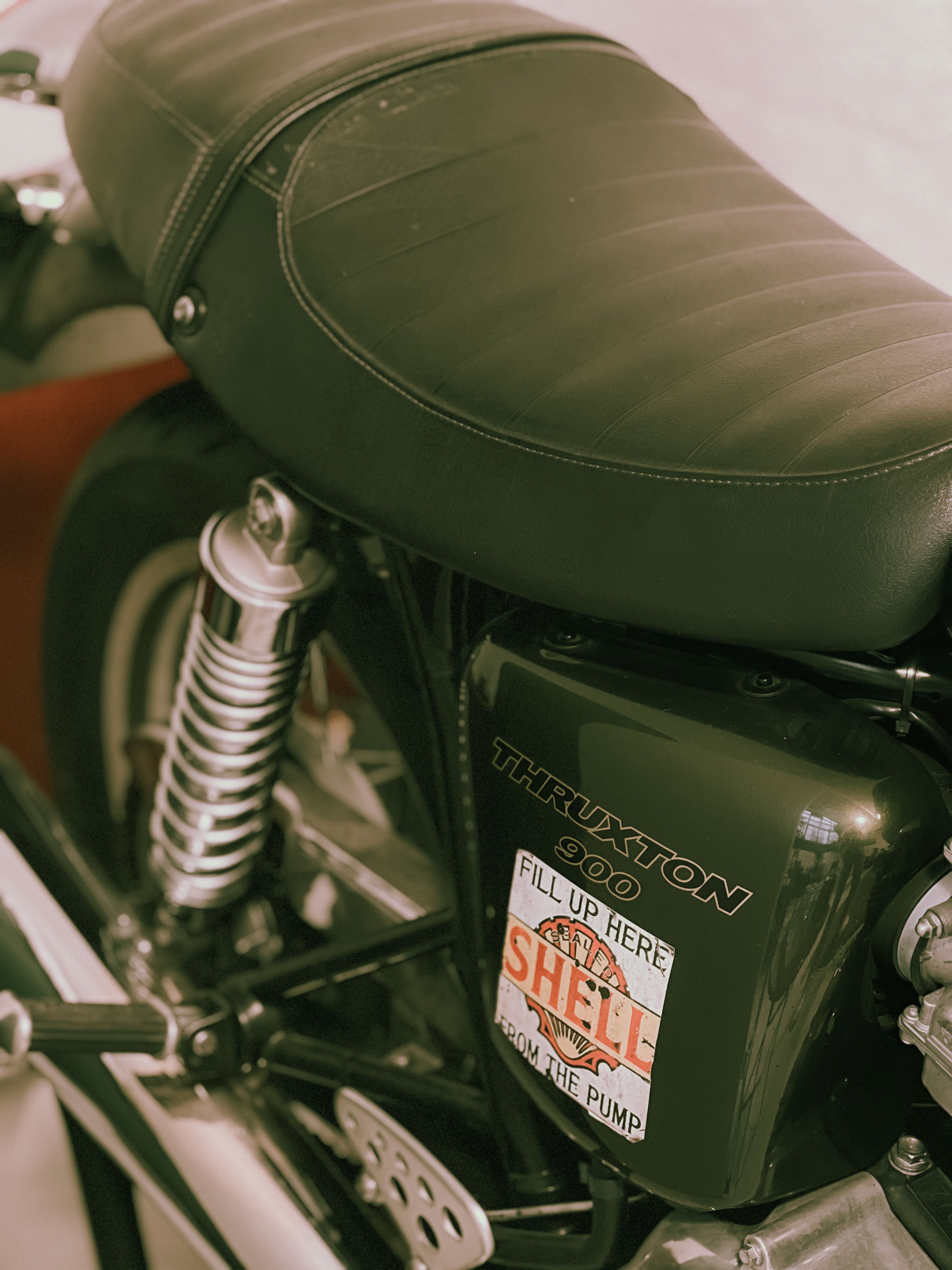 Detailed view of a classic motorcycle's seat and body panel with vintage stickers.