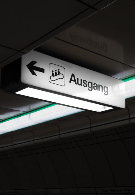 Illuminated 'Ausgang' exit sign in Bochum's subway station with arrow and escalator icon.