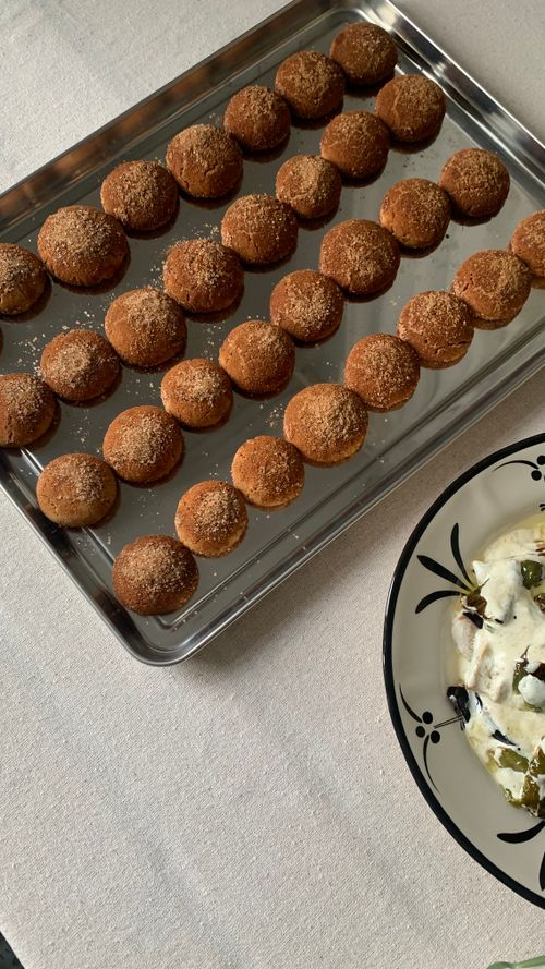 Free Top view of cinnamon-sprinkled dessert balls on a tray beside a yogurt dish. Perfect snack or sweet treat. Stock Photo