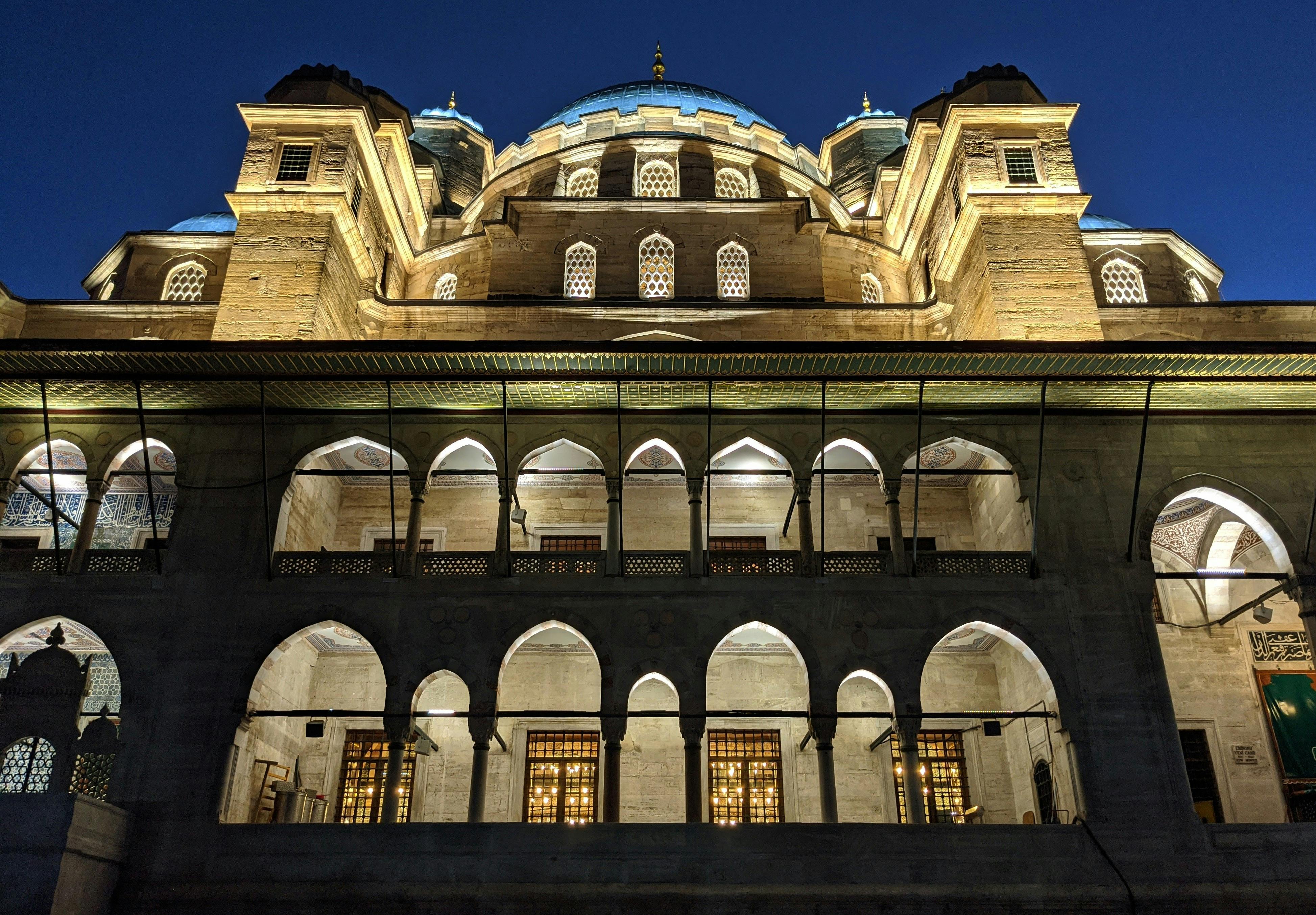 The Yeni Cami Mosque in Istanbul illuminated during the evening, showcasing its Ottoman architecture.