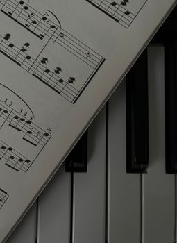 Intimate close-up of piano keys adorned with a musical sheet, capturing a moment of musical artistry.