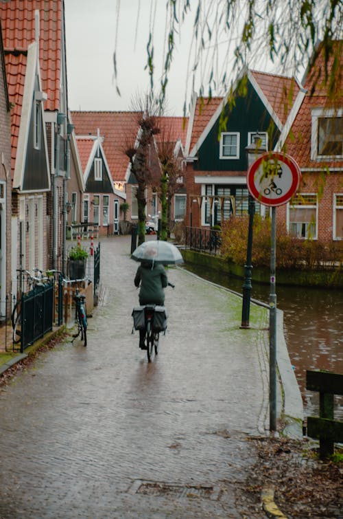 Woman Cycling in Town in Rain