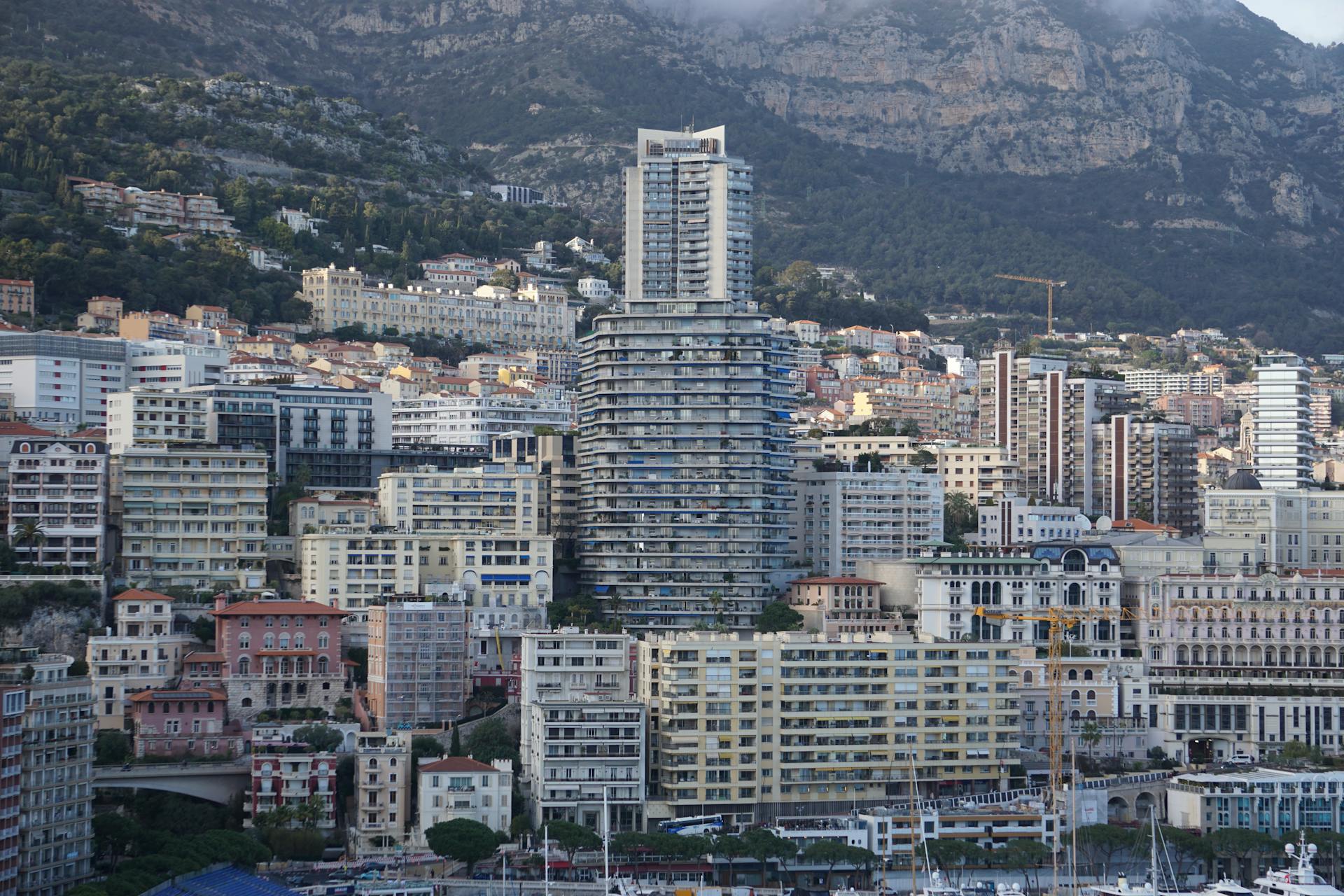 Explore the vibrant cityscape and architecture of Monaco with mountains in the backdrop.