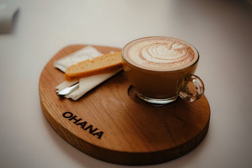 圆形透明玻璃咖啡杯，装满浓咖啡，圆形棕色木制托盘上饰有ohana浮雕