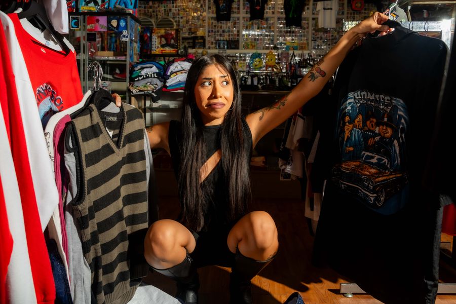 Stylish woman posing with fashion choices in a vibrant clothing store setting.