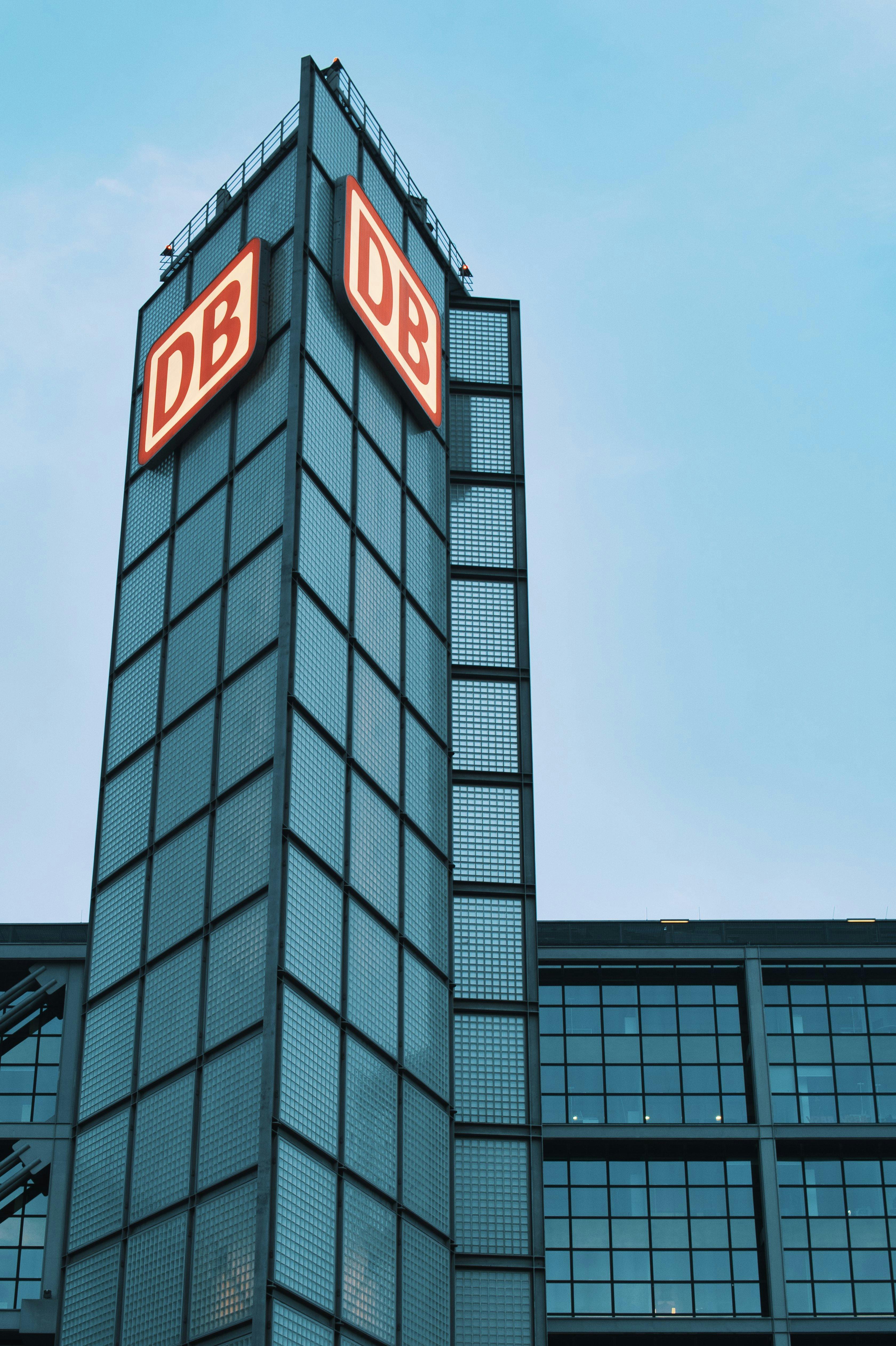 Glass facade of modern building with DB sign in Berlin under blue sky.