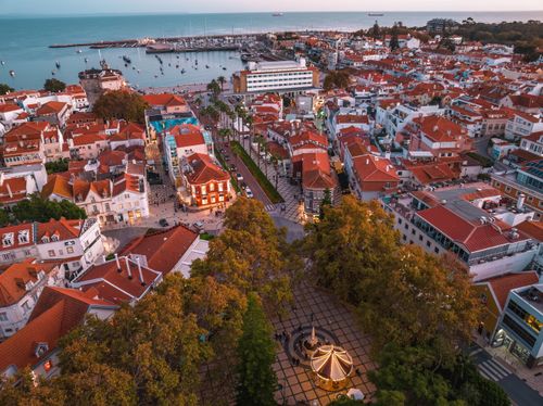 Free Captivating aerial view of Cascais, Portugal, showcasing red-roofed buildings and serene waterfront at sunset. Stock Photo