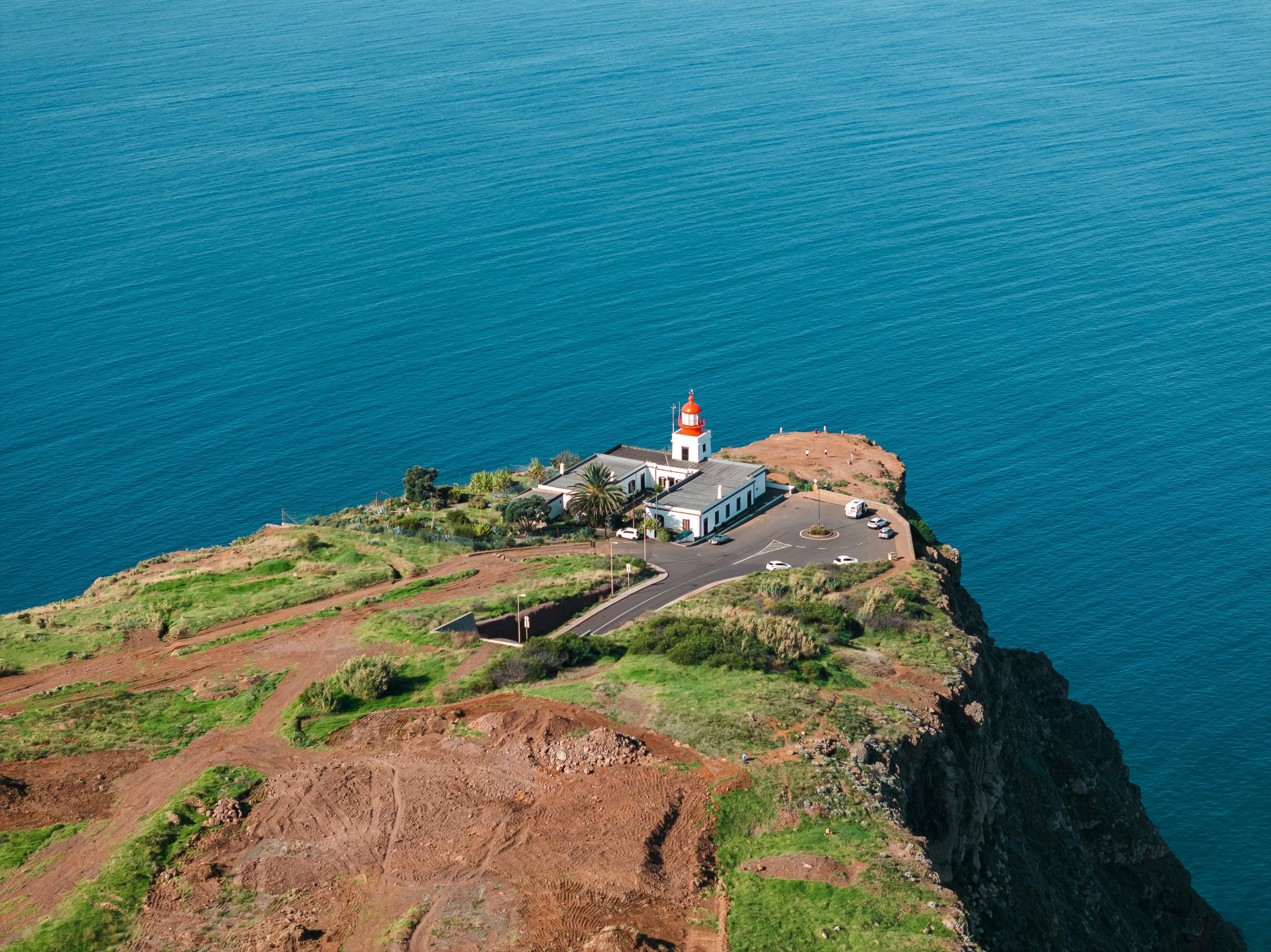 Aerial shot of Ponta do Pargo Lighthouse on a cliff overlooking the Atlantic Ocean in Madeira, Portugal.