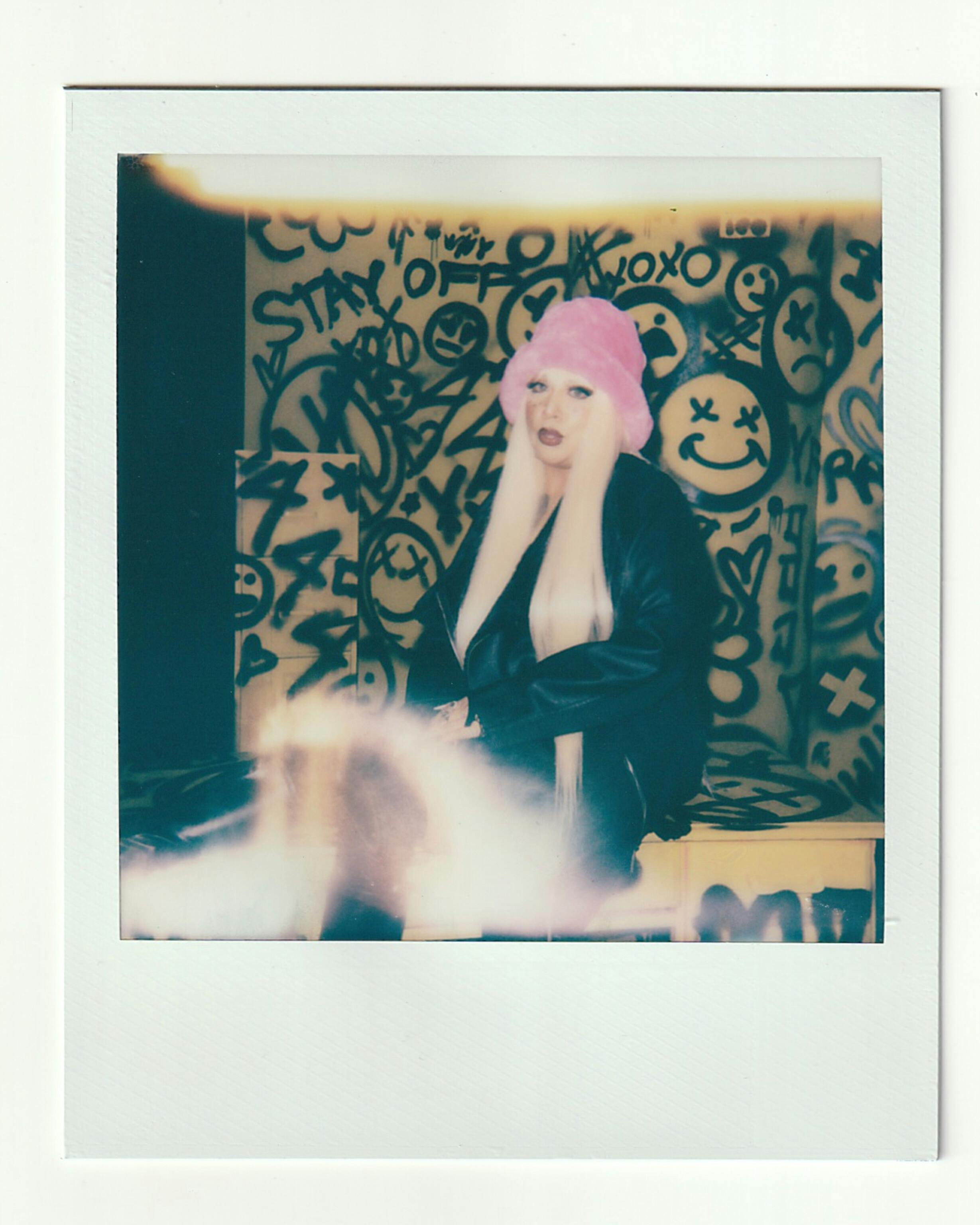 Stylish woman with pink hat in front of graffiti in LA, Polaroid photo.