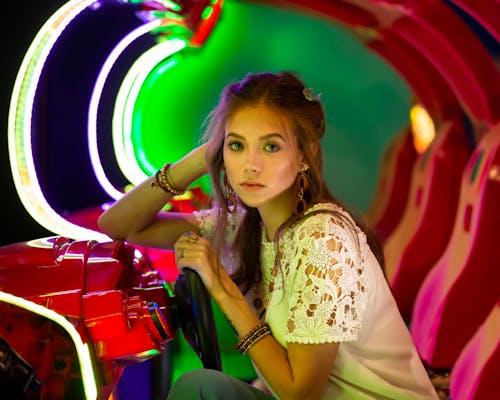 A Girl Sitting behind the Wheel of an Arcade Gaming Machine 