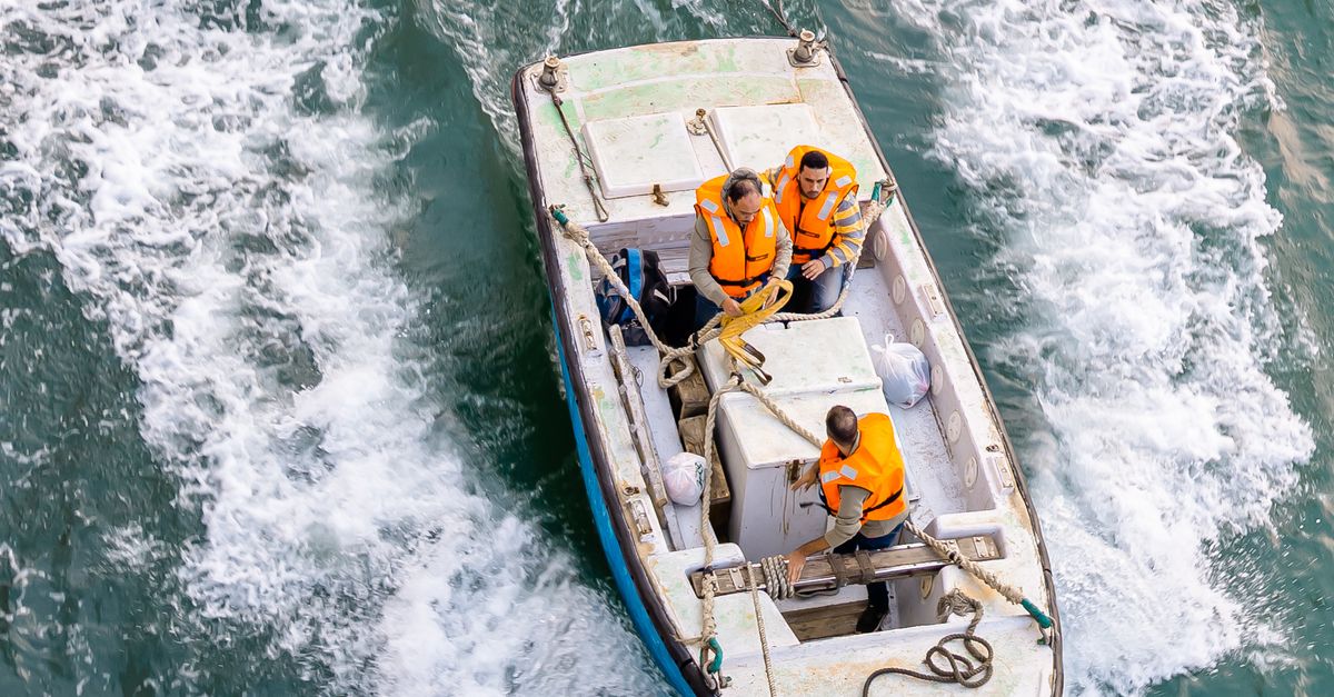 Photo by jefe king Aerial view of a boat navigating through the waters in Suez, Egypt, featuring crew members in safety vests.