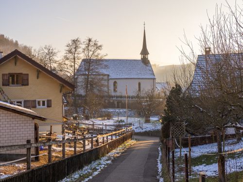 Free Peaceful village street with a church under winter morning light and snow. Stock Photo