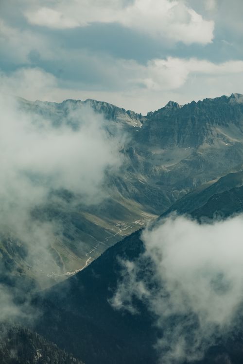 Free Majestic mountains shrouded in clouds create a dramatic natural scene. Stock Photo