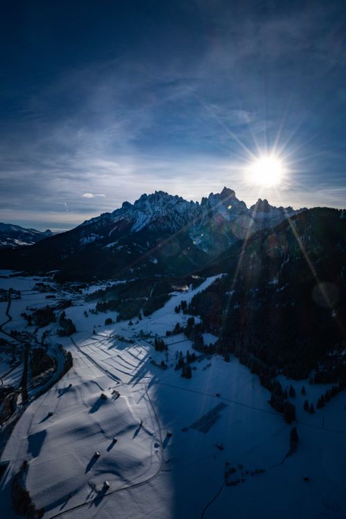 Free A breathtaking aerial shot of snow-capped mountains with bright sunlight casting dramatic shadows. Stock Photo