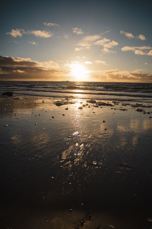 Free Tranquil sunset over the ocean with a reflective beach, capturing warm tones and serene vibes. Stock Photo